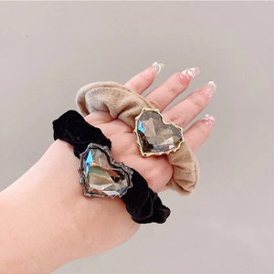 Close-up of velvet hair ties in black and khaki with large heart-shaped rhinestones