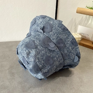 Detailed close-up of light blue denim bucket hat with 3D heart-shaped fabric patches