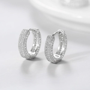 Macro detail of silver-colored hoop earrings with micro-pave white zircon setting
