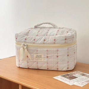 Detail of quilted cotton makeup bag featuring red floral patterns and a sturdy zipper handle