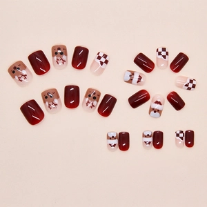 Detailed view of Christmas press-on nails with reindeer and red plaid patterns