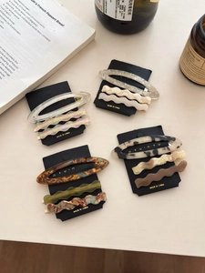 Flat lay of acetate hair clips in tortoiseshell and marble patterns with decor