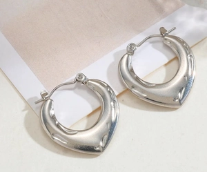 Detailed close-up of chunky silver hoop earrings with irregular hammered texture surface
