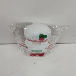 Detailansicht einer Weihnachts-Stoffpuppe mit Kochmütze in einer transparenten Tüte