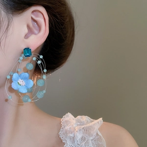 Close-up of model wearing blue fabric flower earrings with beaded tassels and gemstones