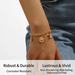 Detail of chunky gold chain bracelet featuring radial heart disc and flower charms