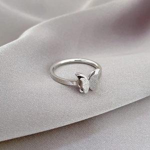 Macro shot of minimalist butterfly ring showing contrast of frosted wings and polished band