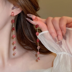 Detail of long strawberry crystal tassel earrings on model showing length and movement