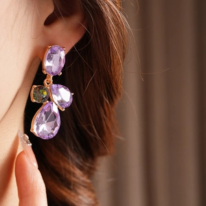 Close-up of vintage drop earrings with purple amethysts and gold metal on model