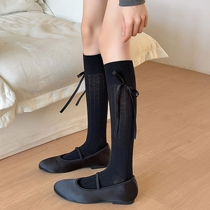 Detail of black calf-length socks with ribbon bows and satin Mary Jane shoes for girls