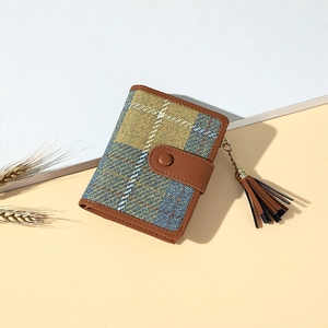 Detail of yellow and blue checkered fabric wallet with brown leather clasp and tassel