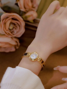 Detail of elegant gold bracelet watch with tortoise shell links on a female wrist