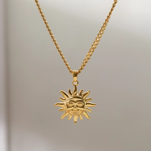 Macro shot of vintage gold sun face pendant with textured twist rope chain necklace