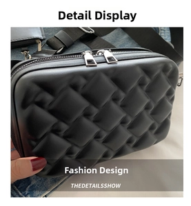 Detail of black woven crossbody bag featuring silver zippers and a wide fabric strap