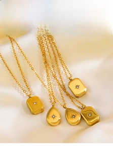 Detail of five gold starburst necklaces with zircon pendants on white silk background
