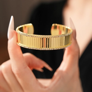 Gros plan d'un bracelet manchette doré avec rayures et bordure en cristaux