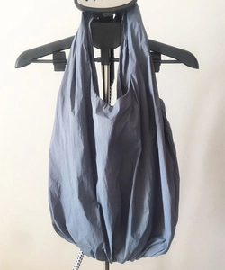 Detail view of a large grey nylon shoulder bag with pleated texture hanging naturally