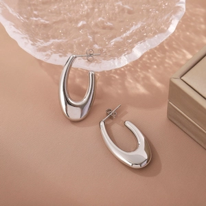 Minimalist silver hollow U-shaped oval earrings displayed on a glass tray