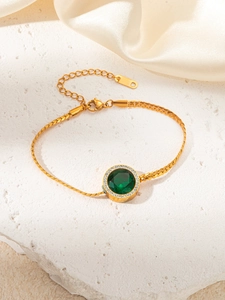 Detail of a gold titanium steel bracelet with a green gemstone and crystal halo
