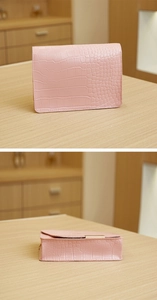Detailed close-up showing pink crocodile texture and gold metal bar on the flip-top handbag