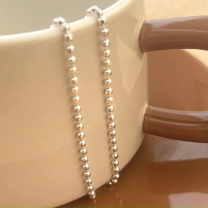 Elegant 925 sterling silver beaded ball chain necklace draped over a ceramic cup
