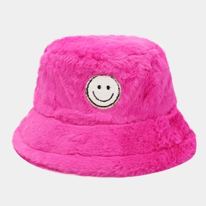 Macro detail of plush pink bucket hat featuring a smiley face patch with gold sequins
