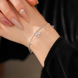 Details des silbernen Doppelarmbands mit Kleeblatt-Anhänger und funkelnden Zirkonia-Steinen