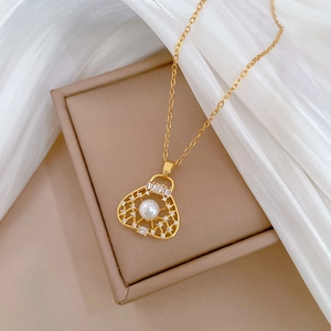 Elegant gold hollow bag necklace with pearl and zircon inlay on soft silk fabric
