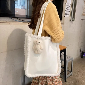 Detail view of white faux fur trim and cute plush bear charm on the shoulder bag