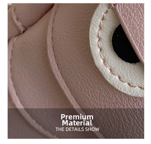 Close-up of pink lychee grain leather stitching and cute cartoon eye detail on a handbag