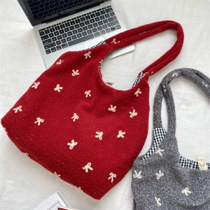 Detail of red and gray tote bags featuring white bow embroidery and plaid lining