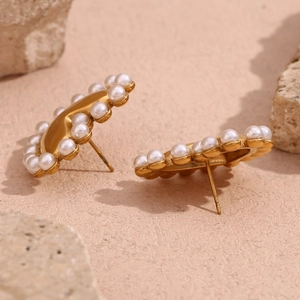 Macro shot of 18K gold plated heart stud earrings with pearl inlay on textured stone