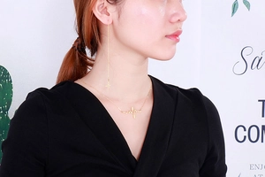 Detailed view of long gold lightning earrings and heartbeat necklace on a female model