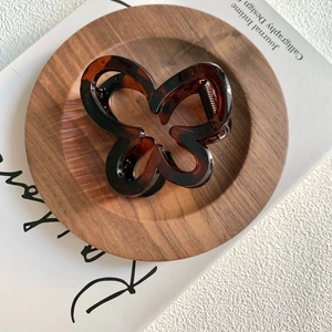Detailed view of butterfly hair claw clip with dark amber tortoiseshell pattern texture