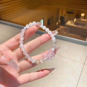 Detail of pink crystal beaded bracelet with transparent bow charm and silver spacers