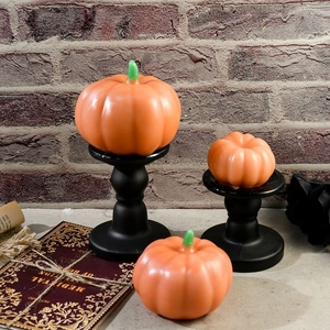 Vista dettagliata di tre candele a zucca arancioni su supporti neri vintage eleganti
