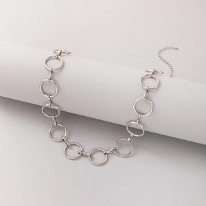 Détail du collier à maillons circulaires argentés présenté sur un socle gris moderne