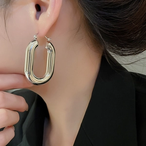 Primo piano di un orecchino a cerchio ovale a forma di U in argento lucido su modella