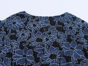 Détail de broderies florales en denim bleu foncé sur tulle noir avec texture effilochée