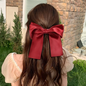 Detailed view of large red satin bow hair clip styled on hair for elegant back look
