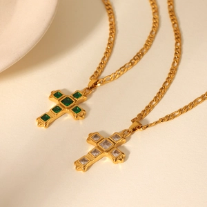 Detail of gold Figaro necklaces with cross pendants featuring green and clear zircons