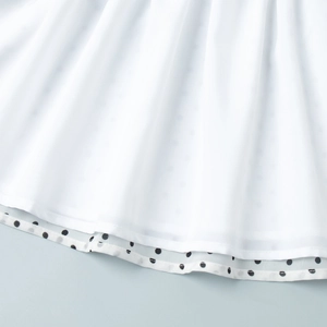 Detail of double-layered white chiffon hem with polka dot lining and elegant pleats