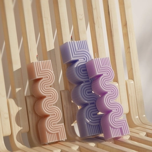 S-shaped wavy geometric scented candles in pink, purple, and blue with vertical textures