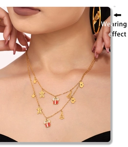 Detail of double-layer gold necklace with enamel Christmas charms on a female model