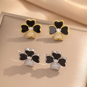 Detail of gold and silver four-leaf clover earrings with black enamel and zircons