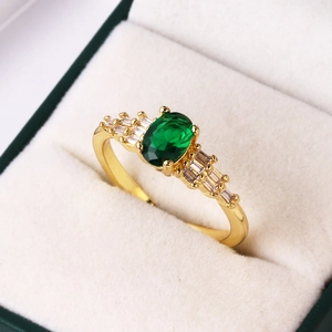 Macro shot of oval green gemstone ring with side baguette crystals on velvet