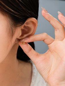 Close-up of 14K gold plated heart stud earring held by hand for a size demonstration