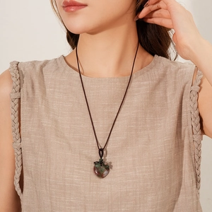 Detail of hand-woven cord necklace with vintage heart-shaped green stone pendant