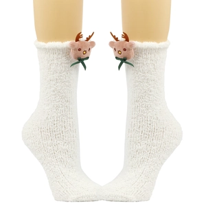 Detail von weißen Plüschsocken mit Rentierpuppe und grüner Schleife für Weihnachten