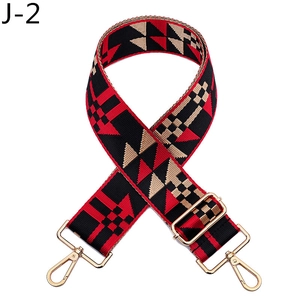 Detail of wide woven bag strap with red and beige geometric patterns and gold metal buckles